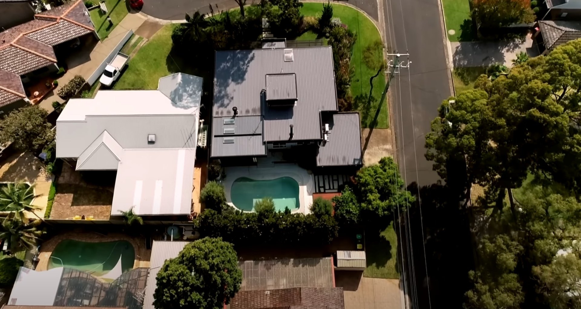 Comprehensive Residential Landscaping and Pool Area Design Aerial view of residential property with professional lawn care, mature landscaping, pool area maintenance, and comprehensive landscape services